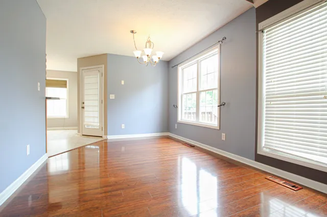 a view of an empty room with window and wooden floor