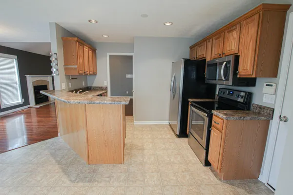 a kitchen with stainless steel appliances granite countertop a refrigerator a stove a sink and a microwave