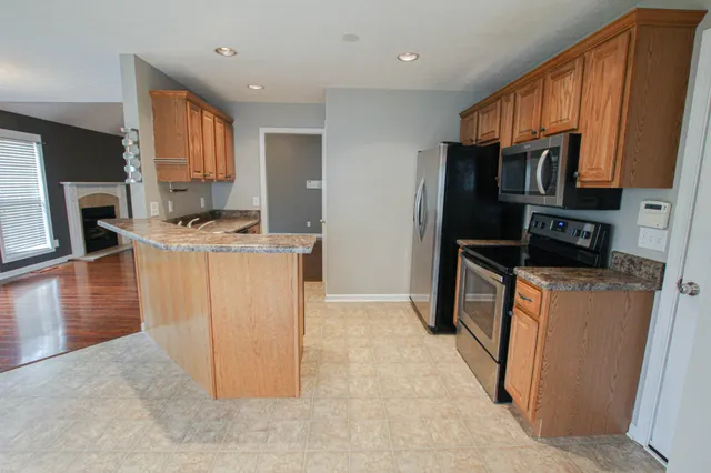 a kitchen with stainless steel appliances granite countertop a refrigerator a stove a sink and a microwave