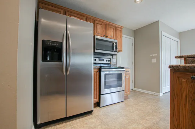 a metallic refrigerator freezer a stove top oven sitting inside of a kitchen