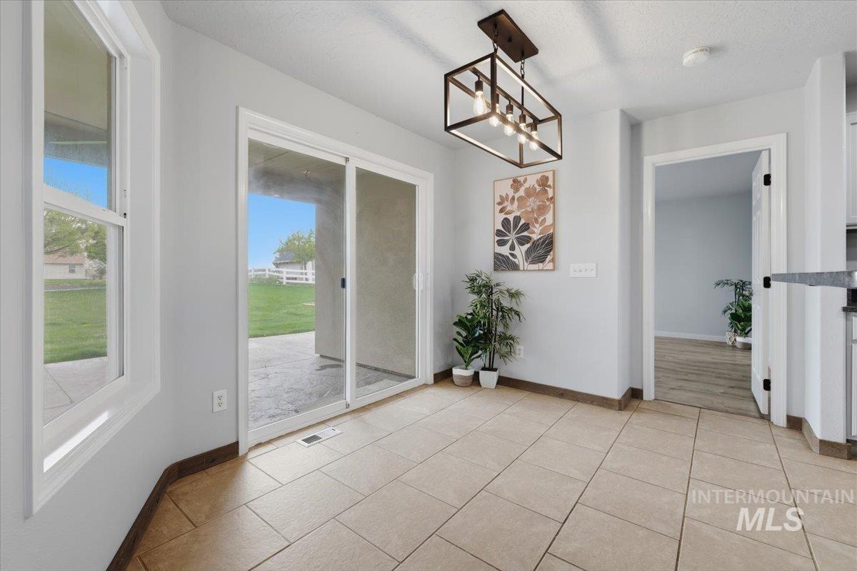 25022 Tumbleweed Road Middleton, ID 83644 - Photo 11 of 41 Unfurnished dining area featuring a chandelier, light tile patterned flooring, and a textured ceiling