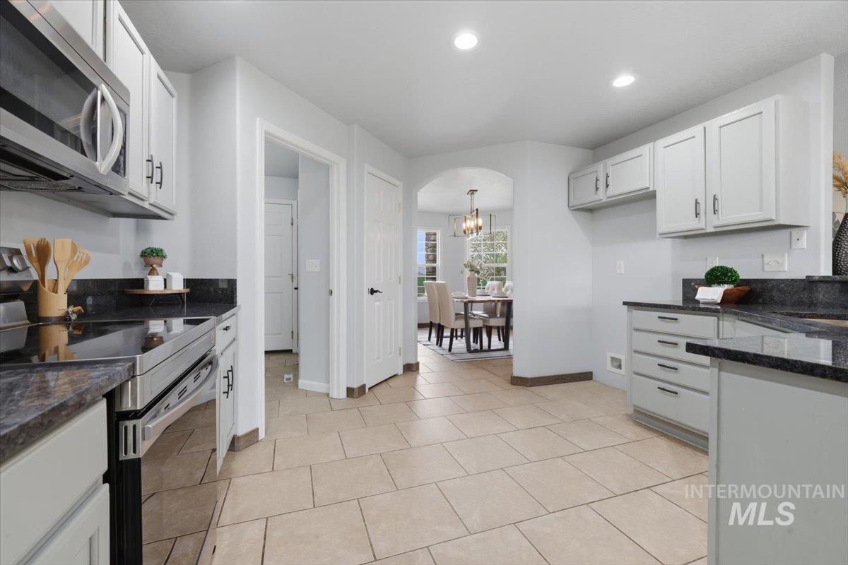 25022 Tumbleweed Road Middleton, ID 83644 - Photo 12 of 41 Kitchen with stainless steel appliances, arched walkways, white cabinetry, dark stone counters, and recessed lighting