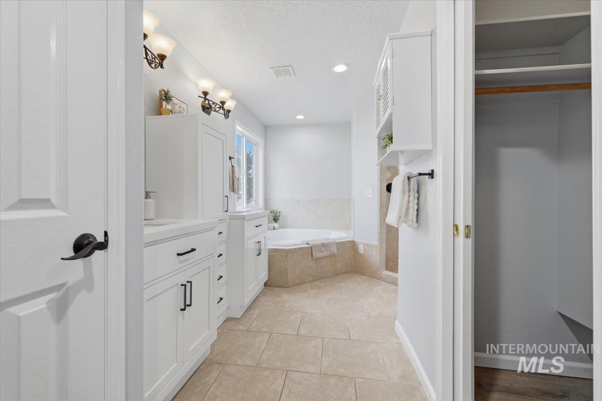 25022 Tumbleweed Road Middleton, ID 83644 - Photo 17 of 41 Full bath with a garden tub, a textured ceiling, vanity, light tile patterned floors, and recessed lighting