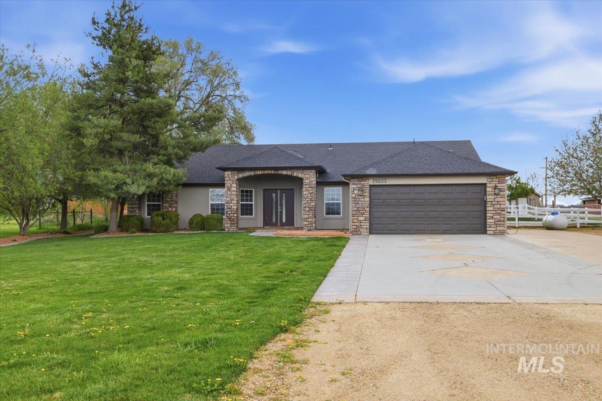 25022 Tumbleweed Road Middleton, ID 83644 - Photo 2 of 41 View of front of house with concrete driveway, roof with shingles, an attached garage, and stone siding
