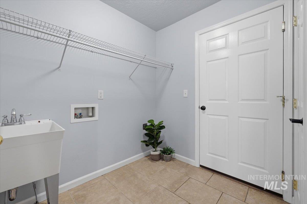 25022 Tumbleweed Road Middleton, ID 83644 - Photo 21 of 41 Laundry room featuring washer hookup, a textured ceiling, and light tile patterned floors