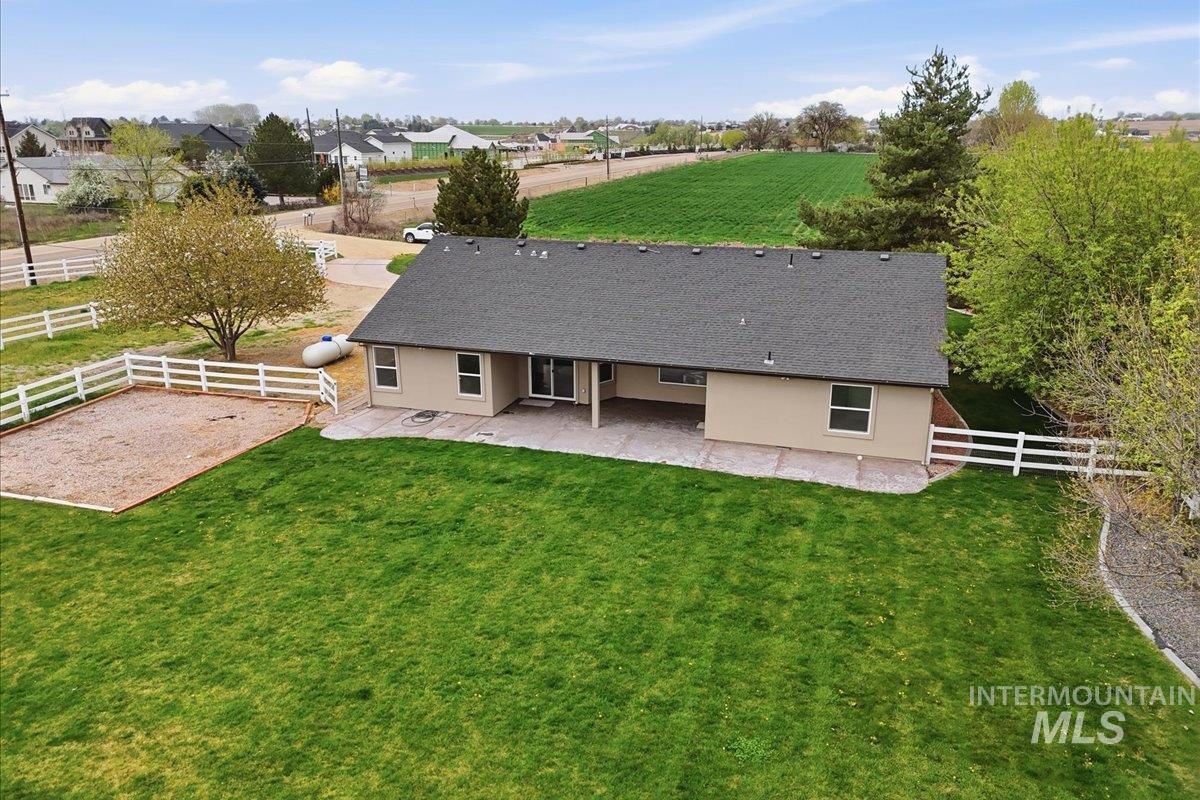 25022 Tumbleweed Road Middleton, ID 83644 - Photo 32 of 41 Back of house with a patio area, a fenced backyard, a shingled roof, and stucco siding