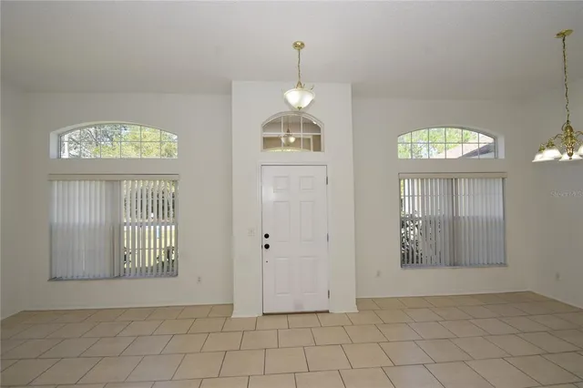 an empty room with wooden floor mirror and windows