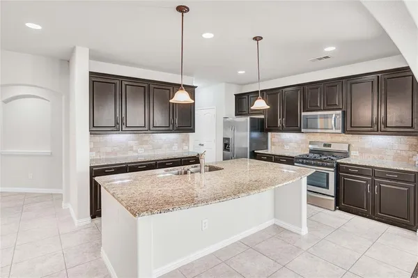 a large kitchen with stainless steel appliances kitchen island a large counter top and a wooden floors