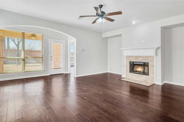 a view of a livingroom with a fireplace a ceiling fan and wooden floor