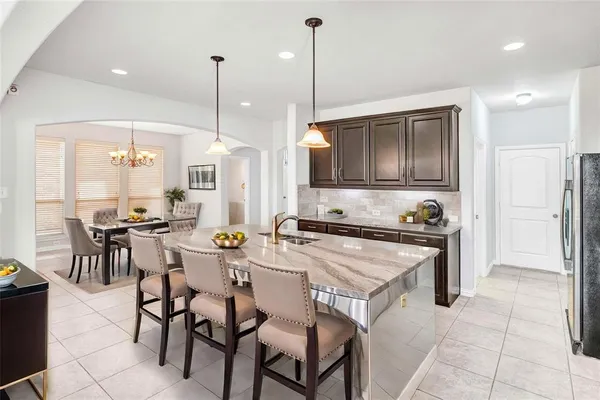a kitchen with stainless steel appliances granite countertop a stove top oven a refrigerator a sink and a dining table