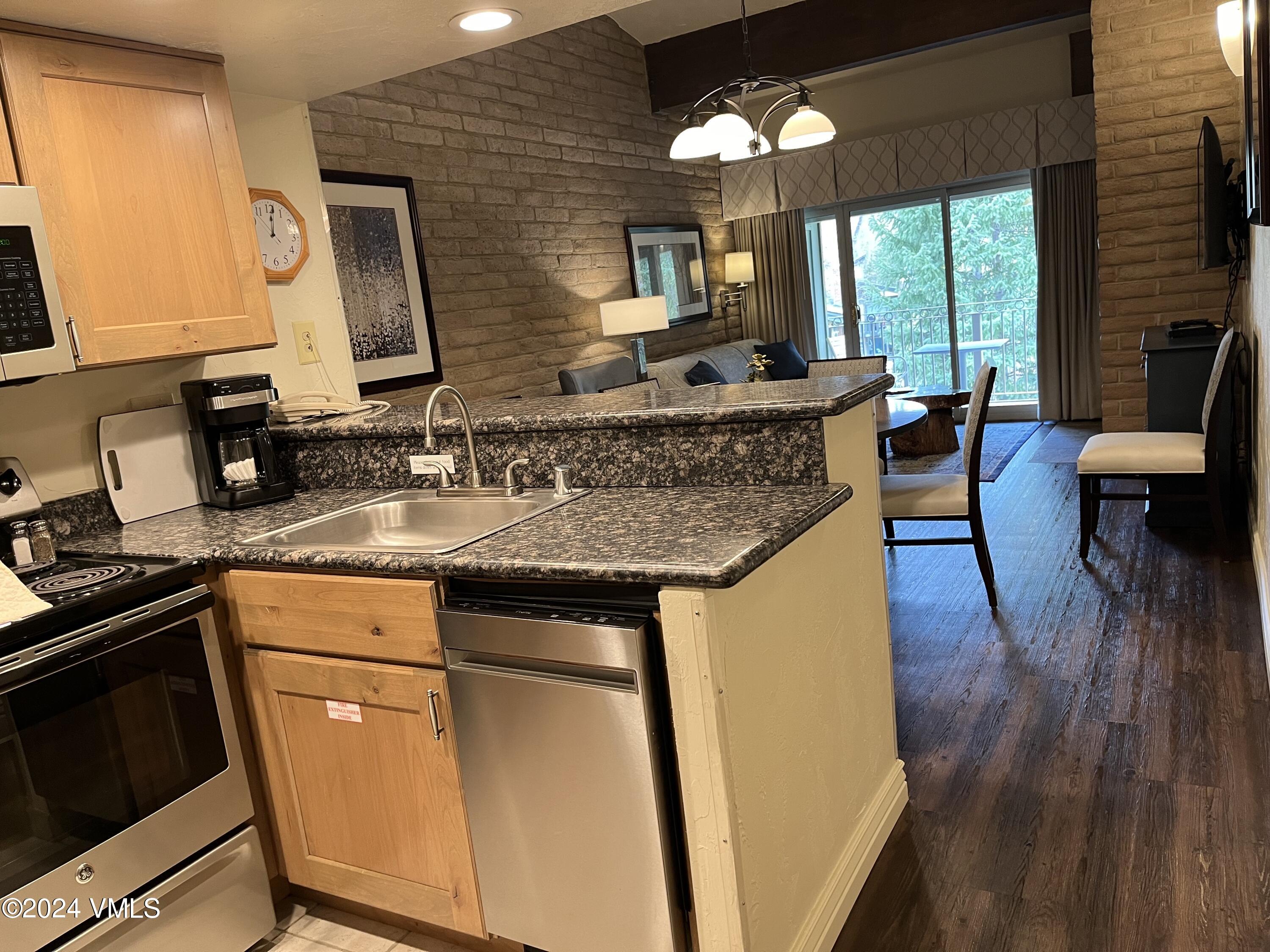 1020 Vail View Drive, Unit 341221 Vail, CO 81657 - Photo 3 of 26 a kitchen with stainless steel appliances granite countertop a sink stove and wooden floor
