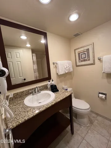 a bathroom with a granite countertop sink a toilet and a mirror