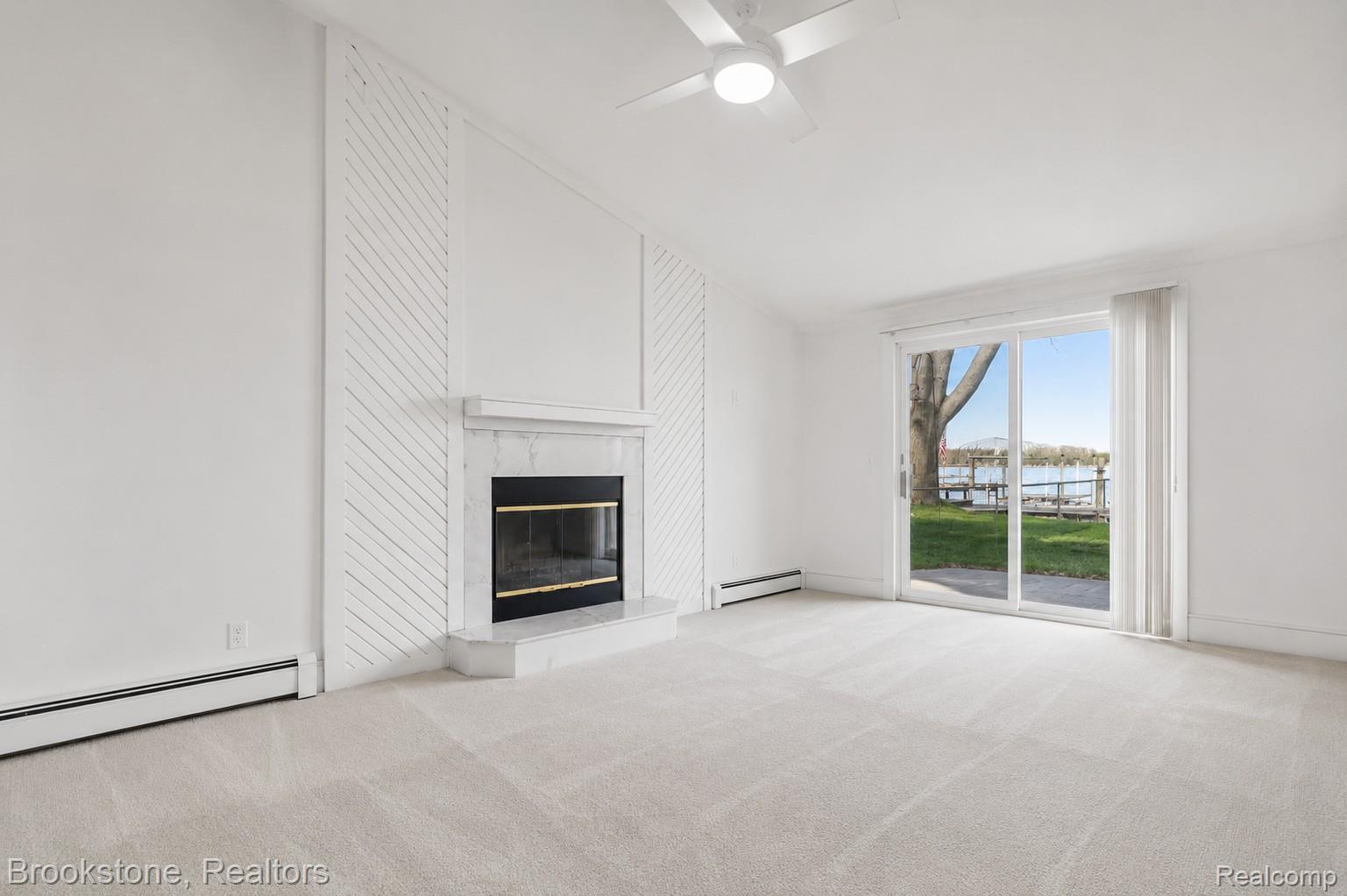 2230 Elm Street Algonac, MI 48001 - Photo 36 of 59 Unfurnished living room featuring a ceiling fan, light carpet, lofted ceiling, a water view, and a premium fireplace