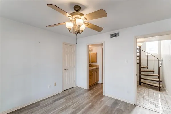 an empty room with wooden floor chandelier fan and windows