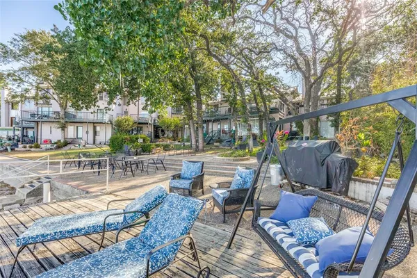 a view of a patio with couches table and chairs and potted plants with wooden floor and fence