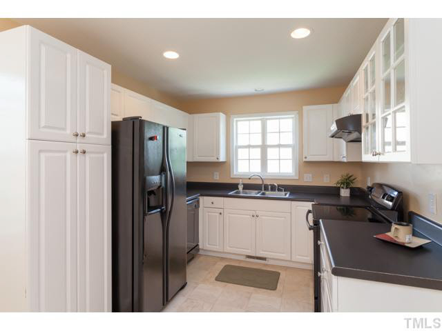 4901 Windblown Court Raleigh, NC 27616 - Photo 8 of 21 a kitchen with stainless steel appliances granite countertop a refrigerator a sink dishwasher a stove a dining table and chairs with wooden floor