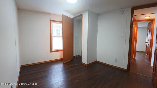 an empty room with wooden floor and windows with curtains