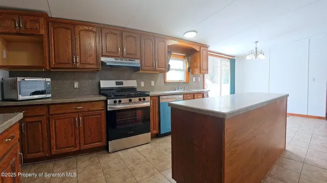 a kitchen with stainless steel appliances granite countertop a stove a sink dishwasher and a microwave oven with cabinets