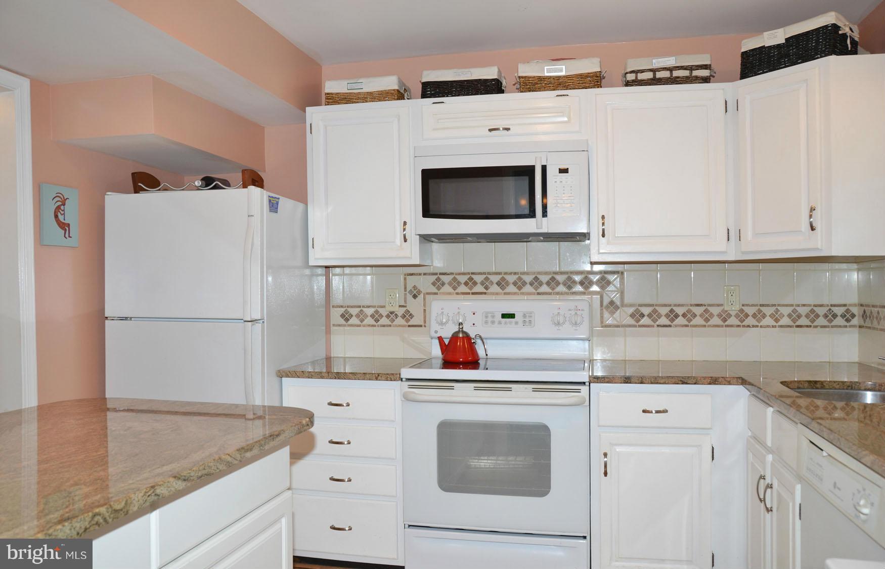 6607 Hillandale Road, Unit 89 Chevy Chase, MD 20815 - Photo 11 of 30 a kitchen with white cabinets and white appliances