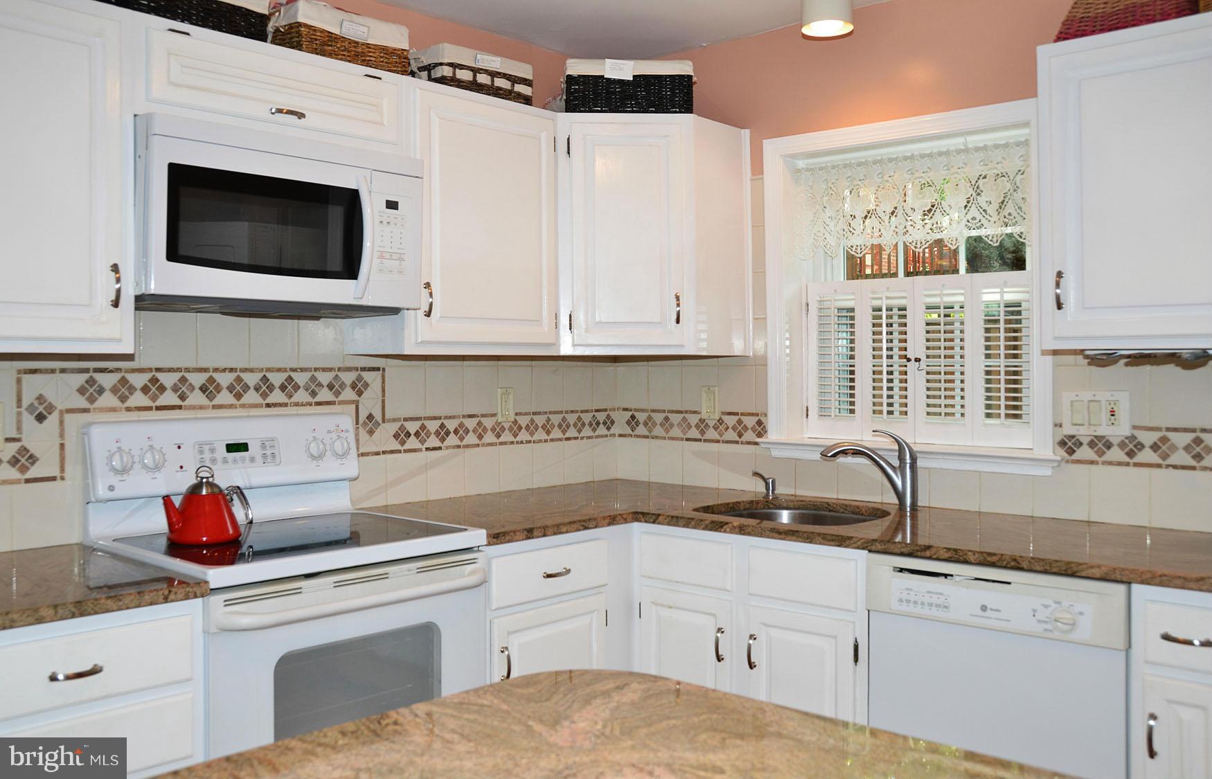 6607 Hillandale Road, Unit 89 Chevy Chase, MD 20815 - Photo 9 of 30 a kitchen with granite countertop a sink a stove and cabinets