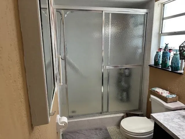 a bathroom with a granite countertop sink toilet and shower