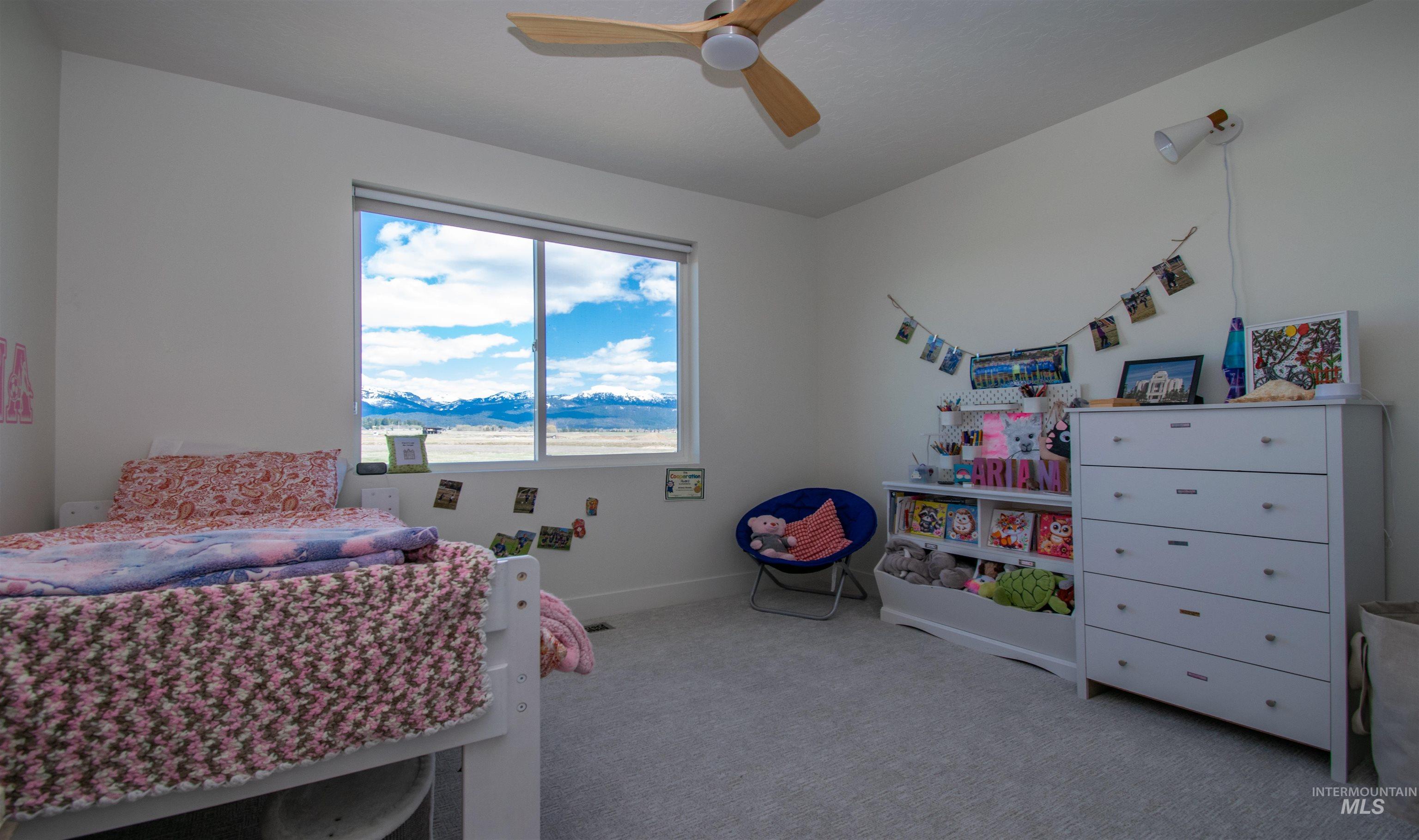 44 Big Moose Road McCall, ID 83638 - Photo 23 of 50 Room featuring a large window, light gray carpeting, neutral wall finishes, a ceiling fan, and a wall-mounted light fixture