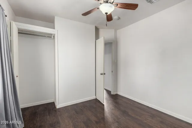 an empty room with wooden floor fan and window