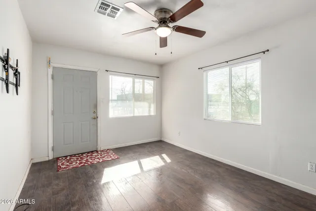 a view of an empty room with wooden floor and a window