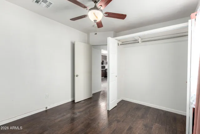 an empty room with wooden floor a ceiling fan and entryway