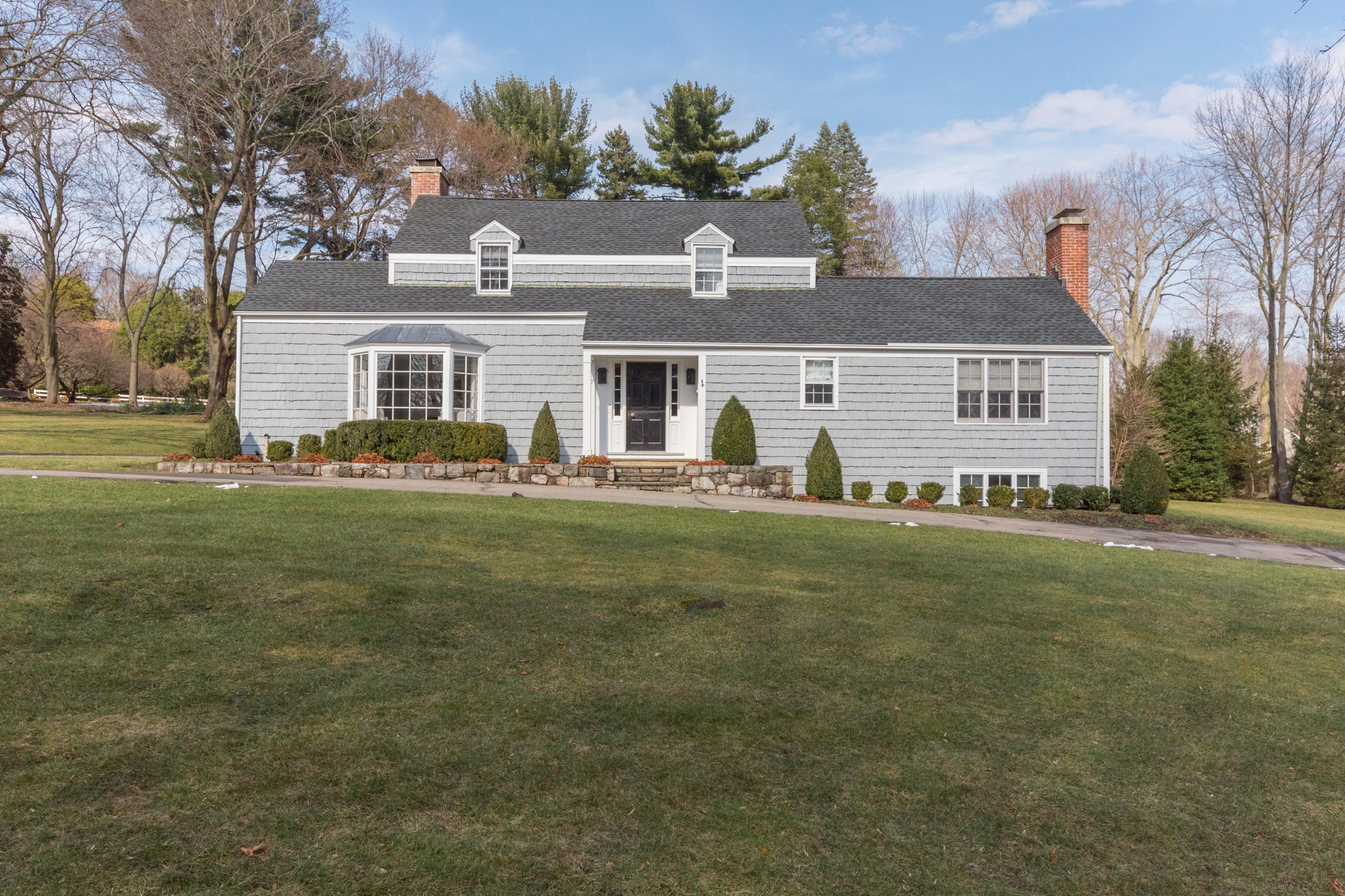 a front view of house with yard and trees in the background
