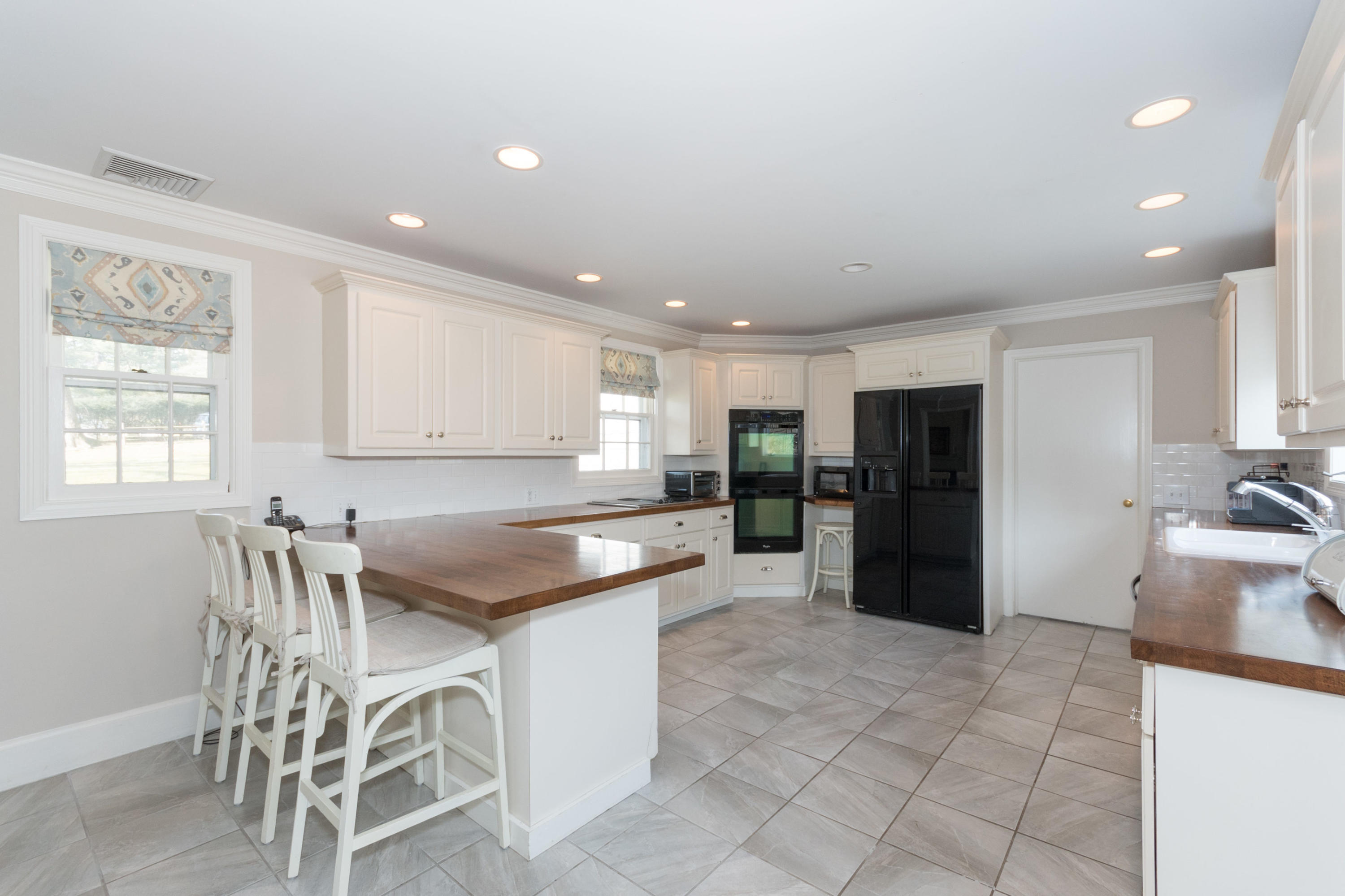 17 Point O Woods Road Darien, CT 06820 - Photo 13 of 44 a kitchen with stainless steel appliances kitchen island granite countertop a refrigerator a stove a dining table and chairs with wooden floor