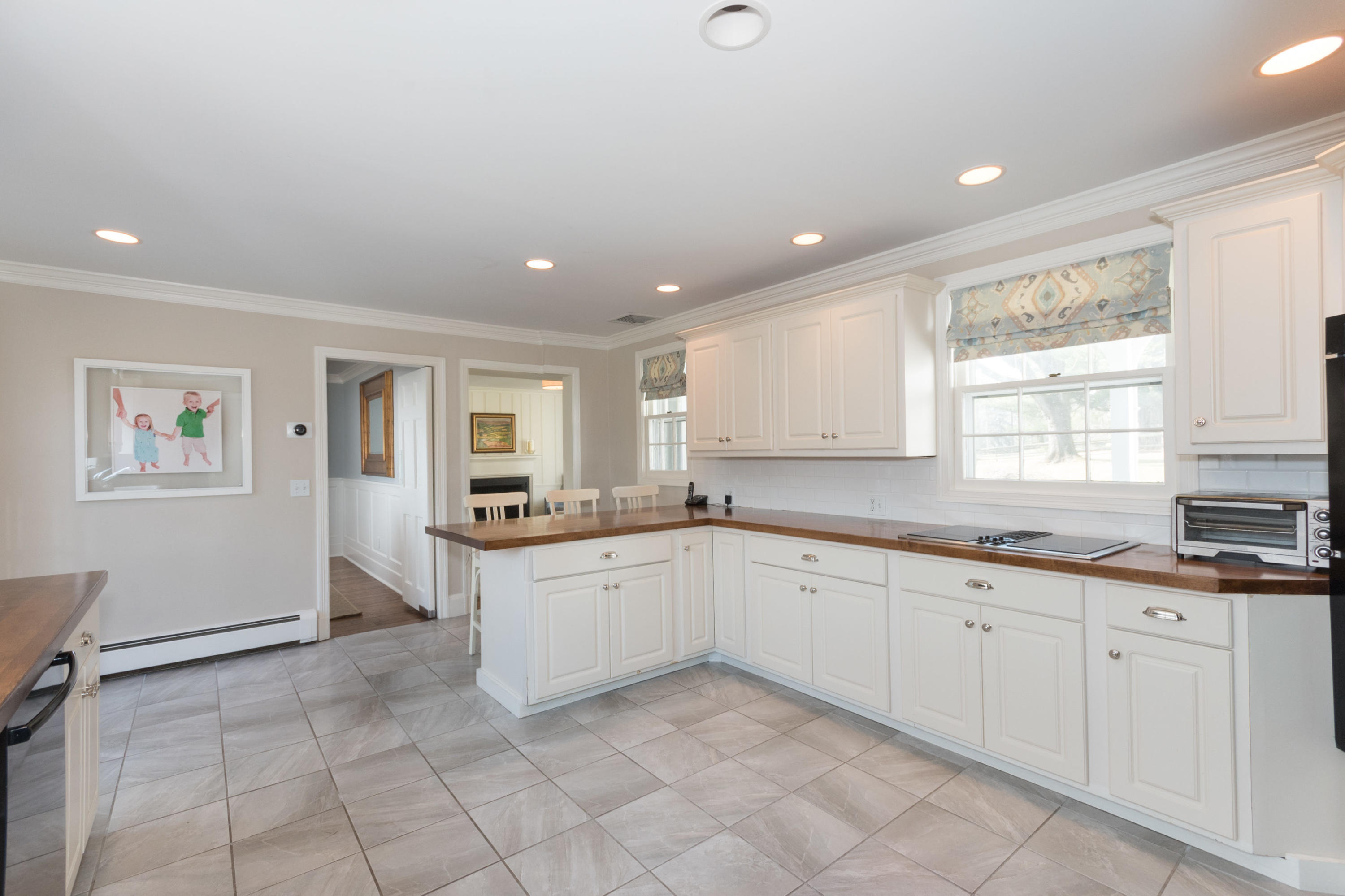 17 Point O Woods Road Darien, CT 06820 - Photo 15 of 44 a large white kitchen with granite countertop a sink white cabinets and a window