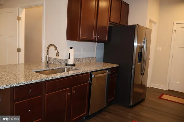 a kitchen with granite countertop a refrigerator and a sink