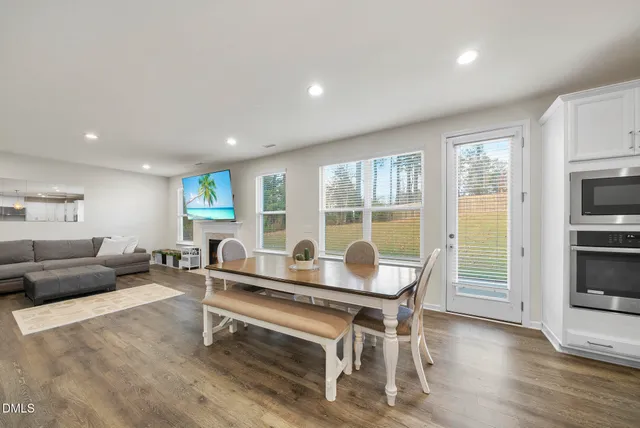 a kitchen with stainless steel appliances kitchen island granite countertop a table chairs and a wooden floor