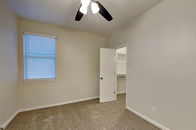 an empty room with a ceiling fan and window