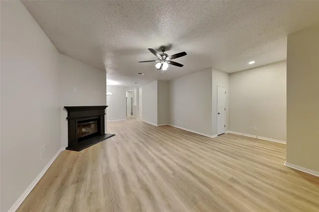 an empty room with wooden floor and a ceiling fan