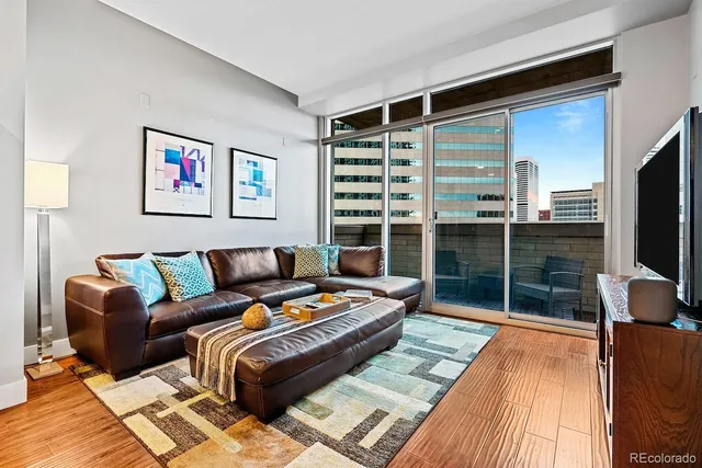 a living room with furniture a flat screen tv and a floor to ceiling window