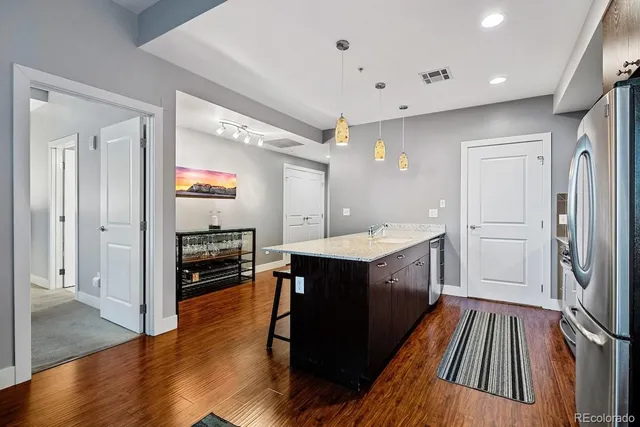 a kitchen with kitchen island stainless steel appliances a sink cabinets and wooden floor