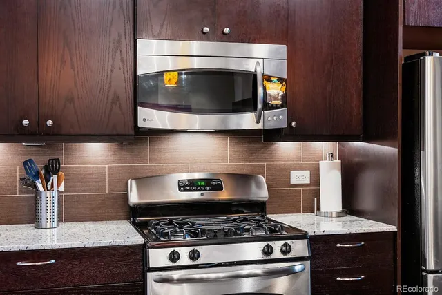 a kitchen with granite countertop a stove a sink dishwasher a dining table and chairs with wooden floor