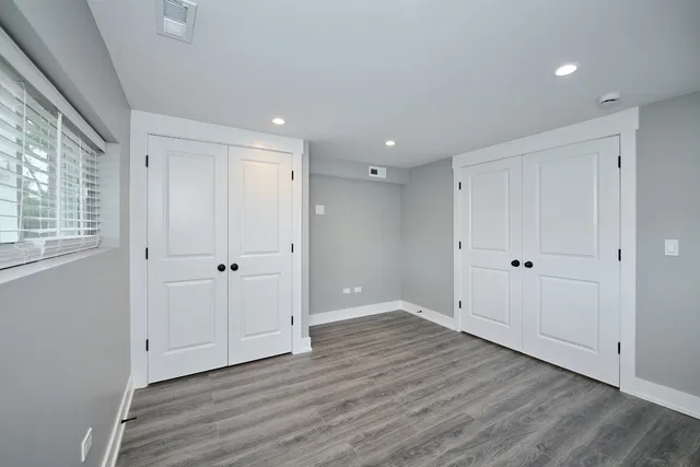 a view of an empty room with wooden floor and windows