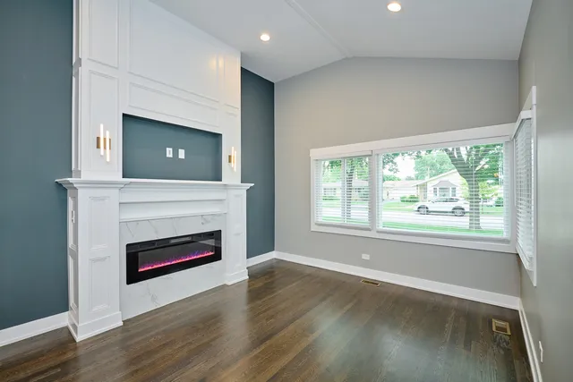 an empty room with wooden floor a fireplace and windows