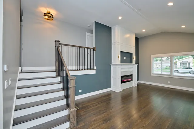 a view of a livingroom with wooden floor staircase and windows
