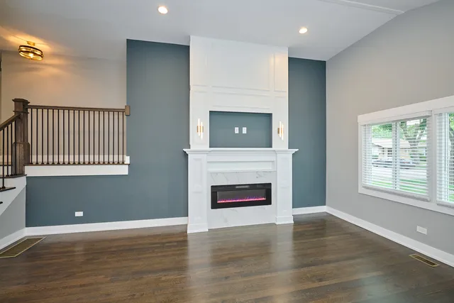 an empty room with wooden floor fireplace and windows