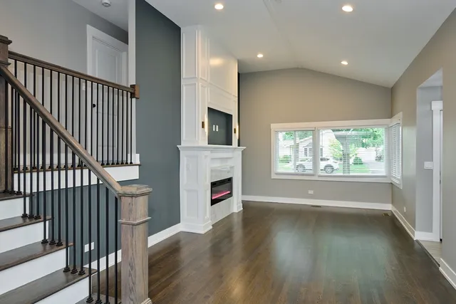 an empty room with wooden floor fireplace and windows