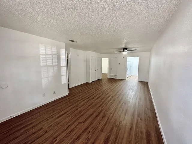 a view of empty room with wooden floor and fan