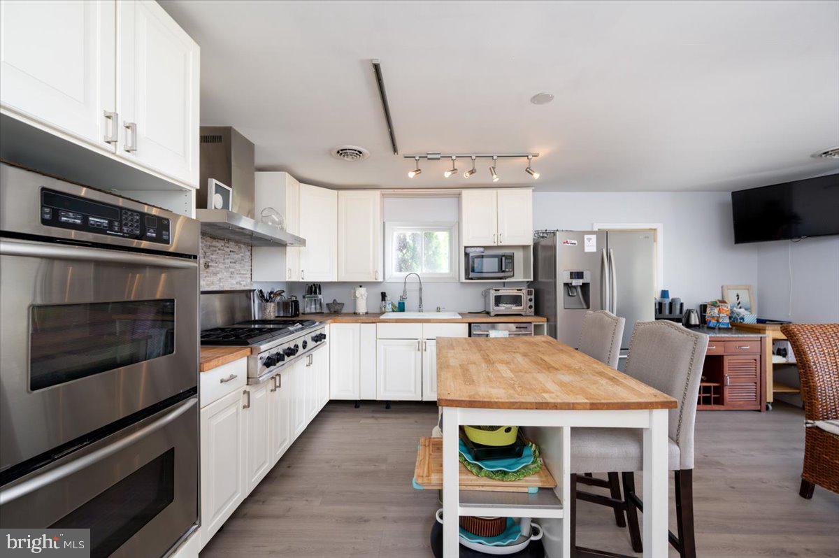 1312 Tuggies Road Pasadena, MD 21122 - Photo 8 of 75 a large kitchen with cabinets wooden floor and stainless steel appliances