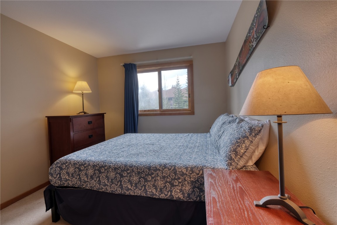 94300 Ryan Gulch Road, Unit 94302 Silverthorne, CO 80498 - Photo 14 of 33 a bedroom with a bed and a lamp on dresser