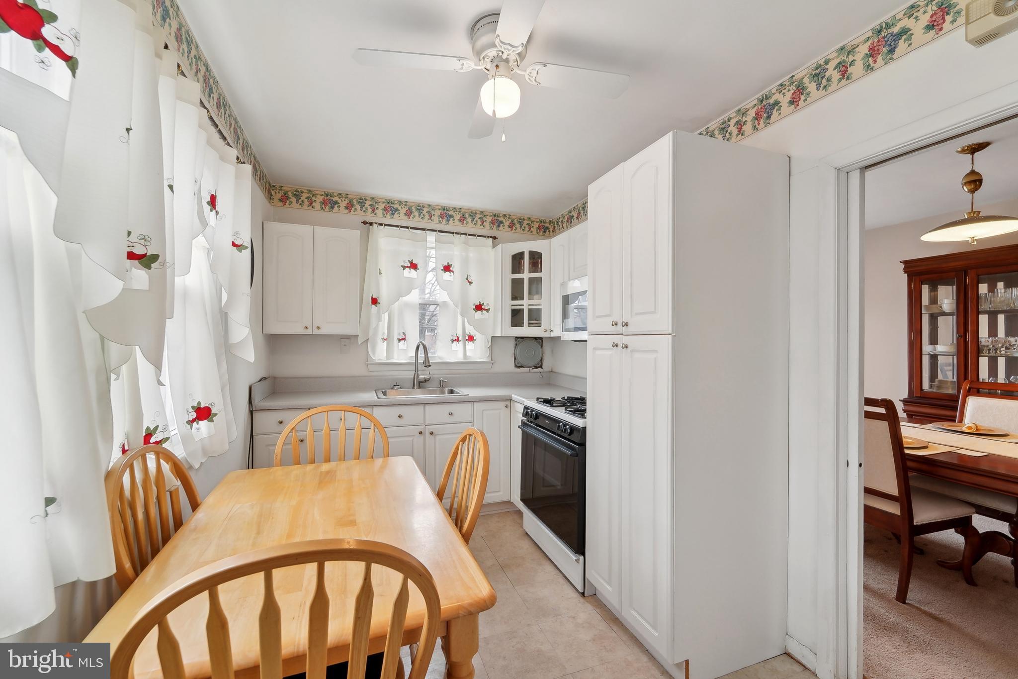 1100 Cedarcroft Road Baltimore, MD 21239 - Photo 13 of 34 a kitchen with stainless steel appliances a white refrigerator a sink dishwasher a dining table and chairs with wooden floor