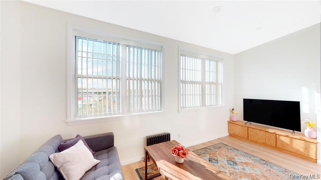 24-12 86th Street, Unit 2 Queens, NY 11369 - Photo 4 of 7 Living area featuring plenty of natural light, light wood finished floors, and radiator