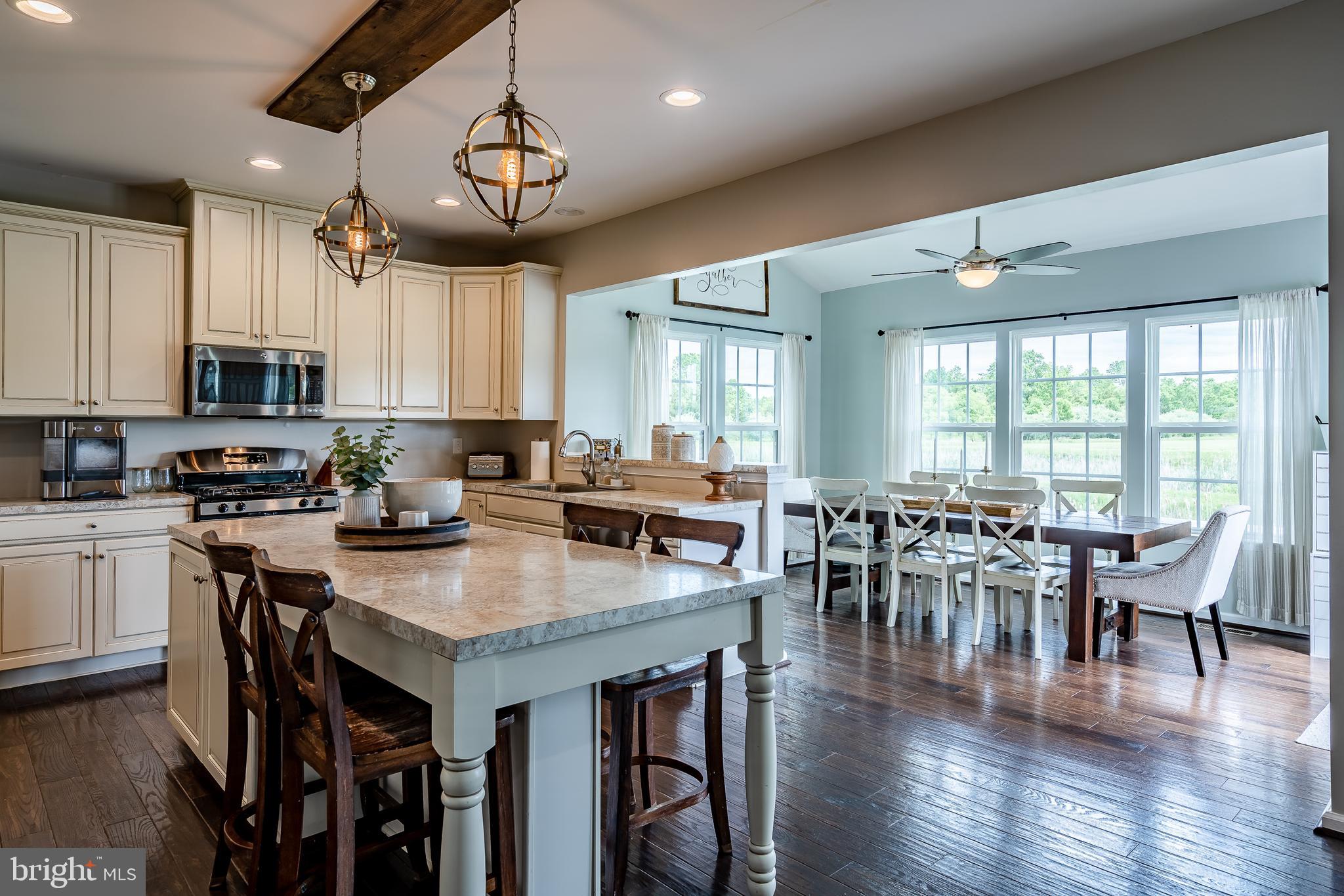 a open kitchen with stainless steel appliances granite countertop a stove a refrigerator a kitchen island a dining table and chairs with wooden floor